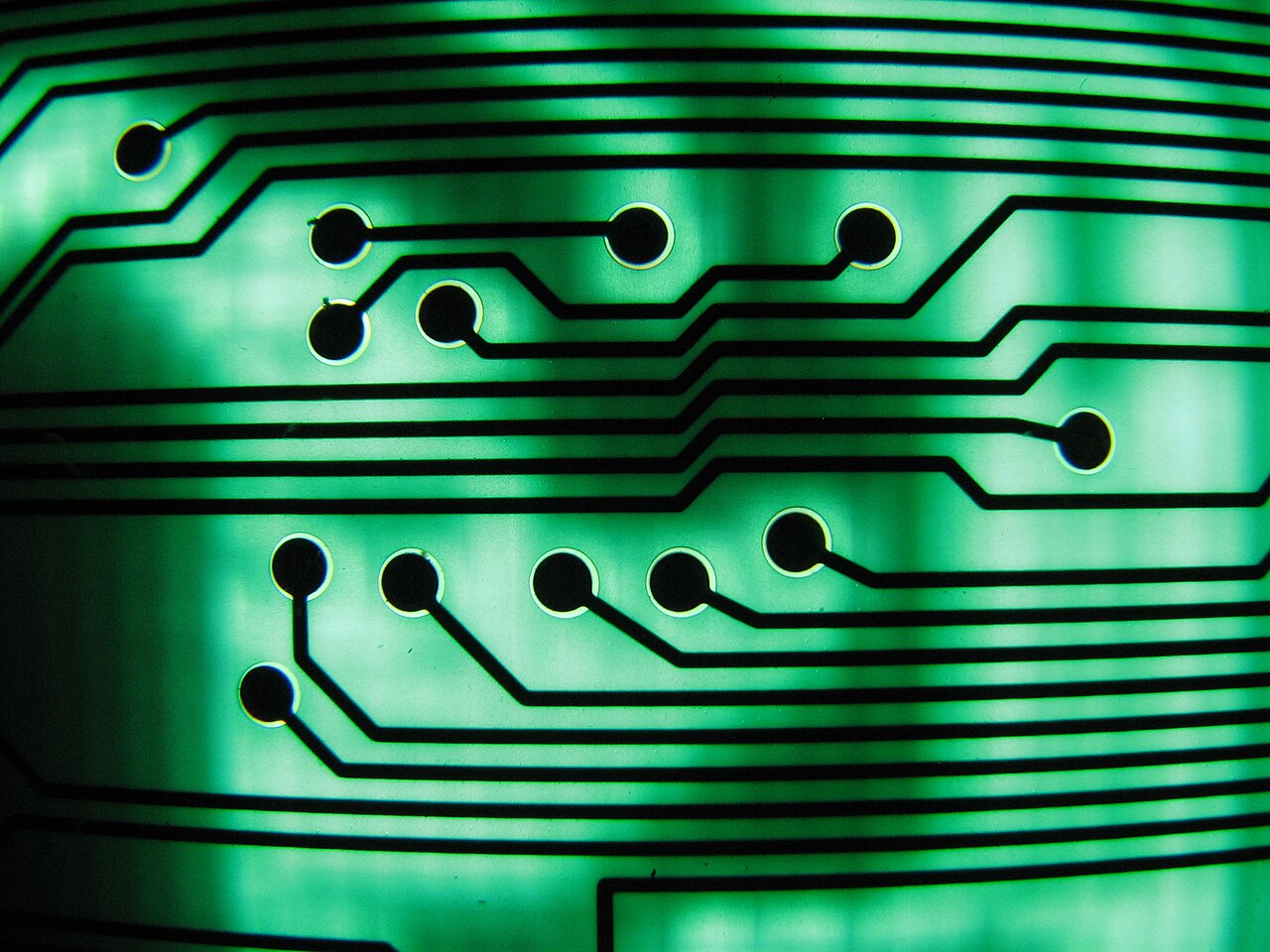 Close-up of a green circuit board with black traces and gold pads