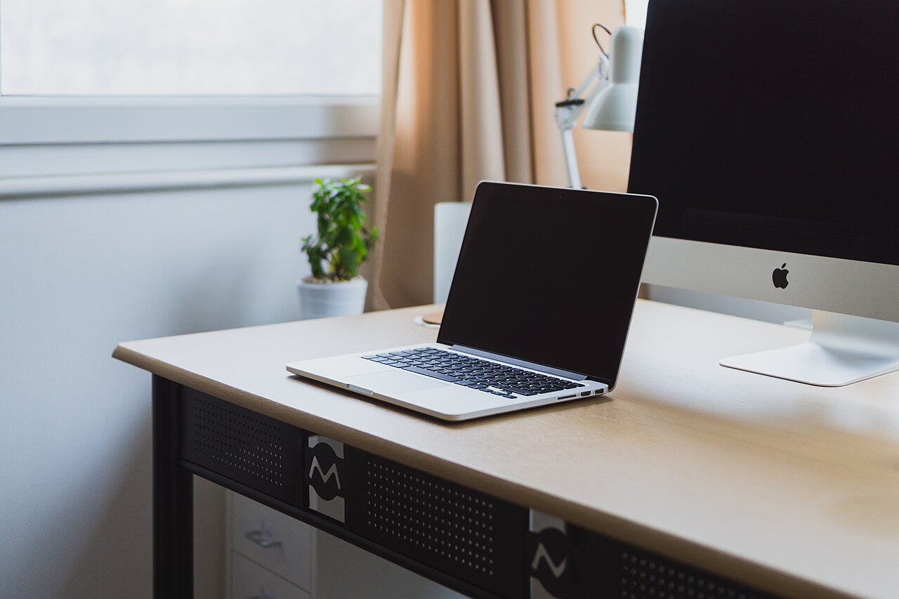 A laptop on a tidy desk beside a monitor, representing an organised Mac workspace